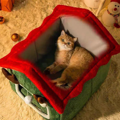 Chat allongé confortablement dans une niche pour chat de Noël verte et rouge.